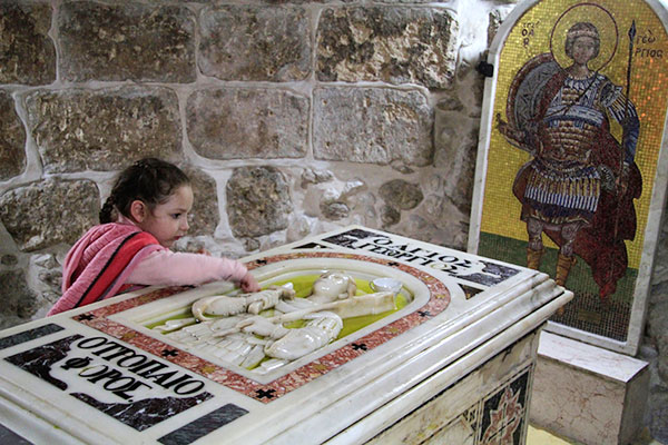 A young girl venerates the tomb of Saint George in Palestine